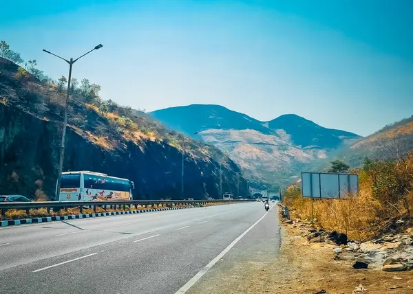 Otoyoldaki araçlar varış noktasına doğru seyahat ediyor ve büyük dağ sırasına bakıyor. 