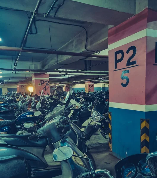 Alışveriş merkezinin yeraltı otoparkı. Park işaretlerine güneş ışığı yansıyor.