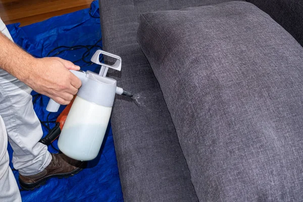 Erkek eli, temiz ve su geçirmez kanepe yastıkları için sıvı dökerken..