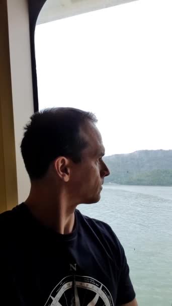 47歳の男 クルーズ船の窓の横に座っている自己ビデオを作る_垂直 — ストック動画