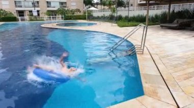 9 year old child doing a somersault over the buoy in the pool and doing the thumbs up sign.