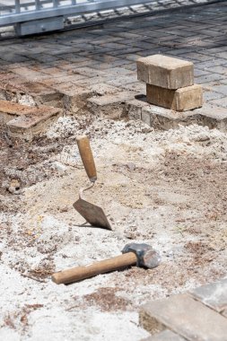 Güneşli bir günde küçük bir tokmak ve beton blokların yanında kumda bir mala..