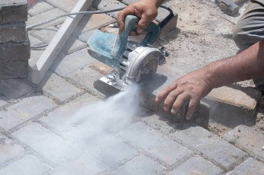Bloğu kesmek için beton testeresi kullanan Brezilyalı inşaat işçisi..
