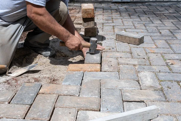 Brezilyalı ve inşaat işçisi beton blokta küçük bir tokmağı vuruyor..