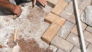 Küçük bir balyoz ile beton bloğu dümdüz eden bir inşaat işçisinin eli yakın plan görüntüsü.