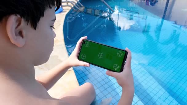 Årigt Barn Sitter Poolen Och Tittar Smartphone Med Grön Skärm — Stockvideo