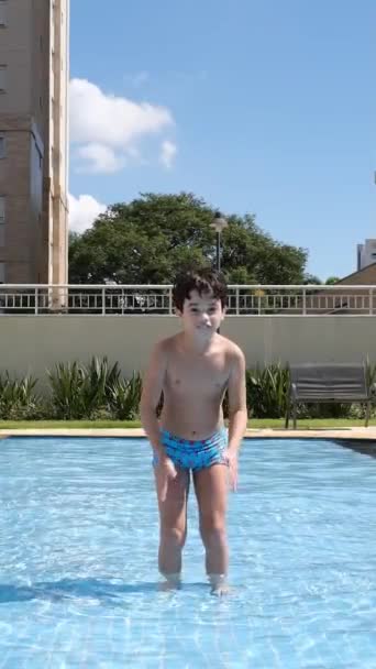 9岁的巴西人在游泳池的浅水区 面对着摄像机 跳跃着滑行着 — 图库视频影像