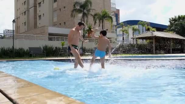 父子俩在阳光灿烂的日子在游泳池踢足球 — 图库视频影像