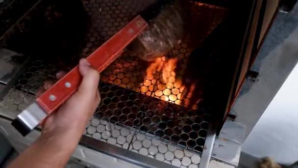 男人用火钳把驼峰牛排扔进烤肉的火中 — 图库视频影像