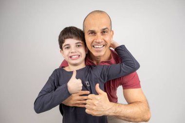 Baba ve oğul kameraya bakıp sarılıyor ve gülümsüyor. Fotoğraflar Stüdyo _ 2 'de.