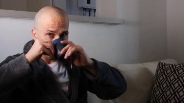 48 yaşında Brezilyalı bir adam çay içiyor, kameraya bakıyor ve yüzünü buruşturuyor..