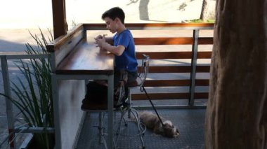 11 yaşında Brezilyalı bir çocuk, dondurmacısı ve köpeğiyle birlikte açık hava dondurma dükkanında oturuyor..