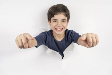 11 yaşında Brezilyalı bir çocuk. Vücudu beyaz bir kartondan çizilmiş ve parmaklarını işaret ediyor..