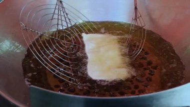 Bir sokak fuarında kızgın yağda iki metal maşayla kızartılan hamur işleri _ yavaş çekim _ b.