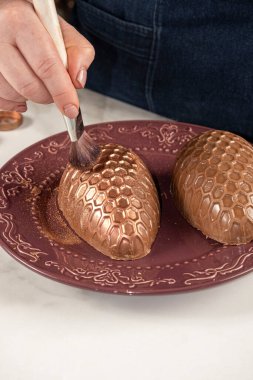 Çikolatalı Paskalya yumurtasını yenebilir bakır tozuyla bal peteği dokusuyla dekore eden şekerci..