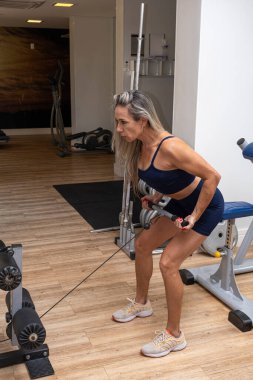 46 yaşındaki Brezilyalı kadın makara makinesinde sırt egzersizi yapıyor _ dikey.