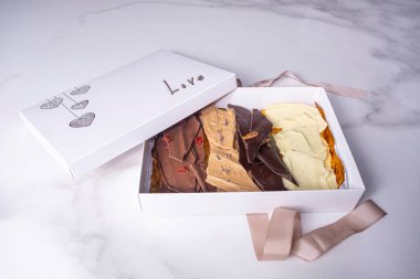 İçinde çikolata parçacıkları ve aşk sözcüğü olan açık beyaz bir kutu..