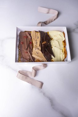 Çeşit çeşit çikolata parçacıkları içeren beyaz bir kutu _ dikey.