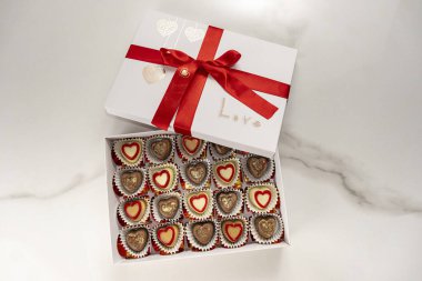 Kırmızı kurdeleli çeşitli çikolatalar ve aşk kelimesi..