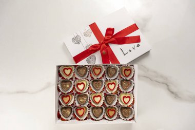 Kırmızı fiyonklu çeşitli çikolatalar ve aşk sözcüğü..