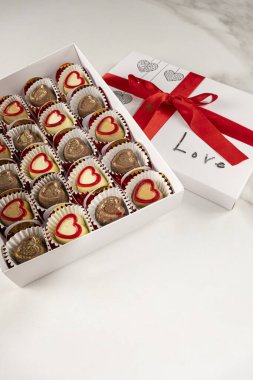 Kapağı açık çeşitli çikolatalar ve kırmızı bir fiyonk _ dikey.