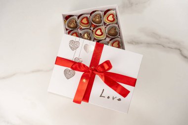 Kapağı açık çeşitli çikolatalar ve kırmızı fiyonk _ üstü görünümü.