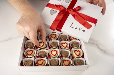 Kırmızı fiyonklu bir kutudan çikolata alan kadın..