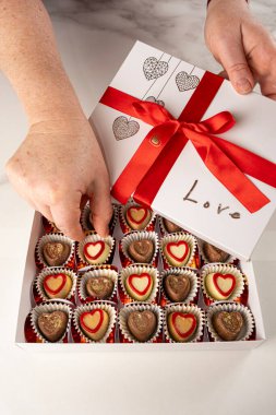 Kırmızı pruva manzaralı bir kutudan çikolata alan kadın..