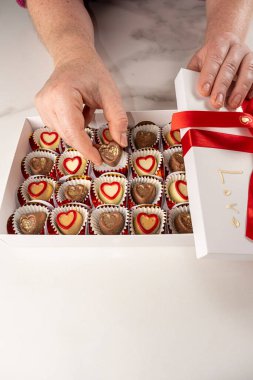 Beyaz bir kutudan çikolatayı alan kadın _ dikey.