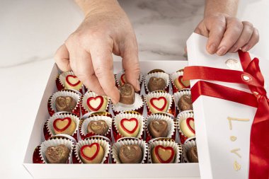 Beyaz bir kutudan çikolatayı alan kadın..