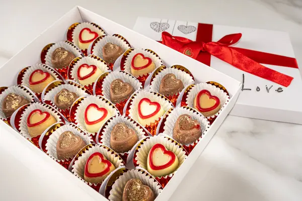 Kapağı açık çeşitli çikolatalar ve kırmızı bir fiyonk.