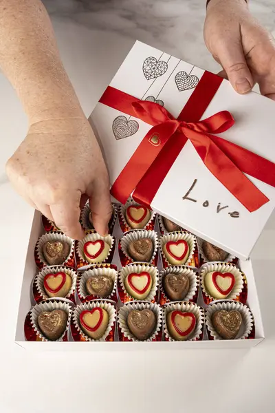 Kırmızı pruva manzaralı bir kutudan çikolata alan kadın..