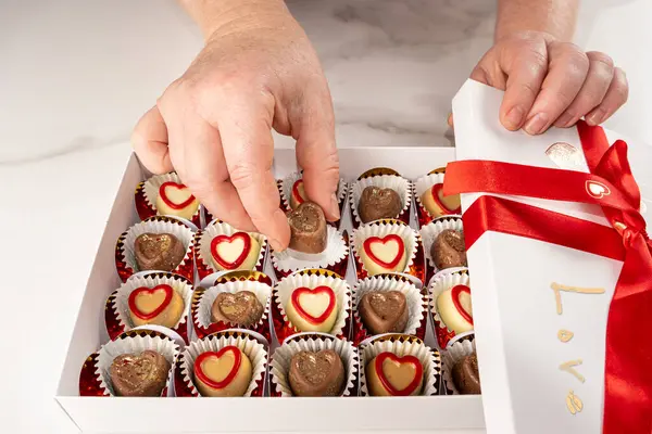 Beyaz bir kutudan çikolatayı alan kadın..