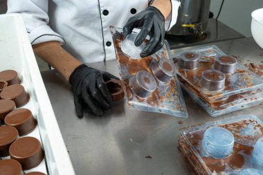 Dairesel çikolata kabuklarını döken fabrika işçisi..