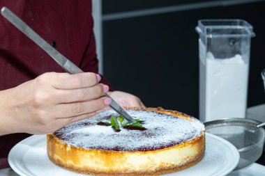 Cheesecake dekorasyonunu naneli yapraklarla bitiriyor..