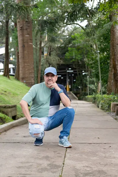 Beyaz gömlekli, kot pantolonlu ve parkta siyah şapkalı yakışıklı bir adamın portresi..