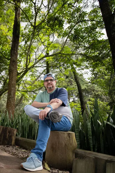 Genç adam bankta oturuyor ve gülümsüyor..