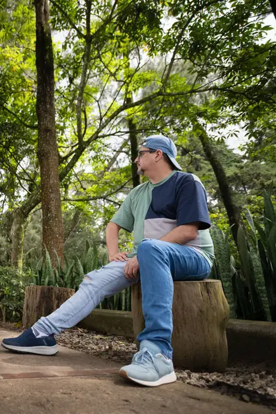 Genç adam ormanda bir bankta oturuyor..