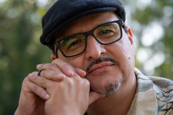 Gözlüklü ve şapkalı olgun bir adam.