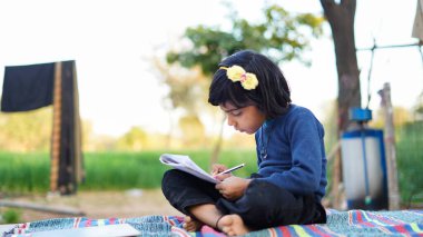 Öğrenci elinde kalemle parkta ödev yapıyor. Okul konseptine geri dönelim. Zavallı Çocuklar Yaşam Tarzı. Eğitim kavramı