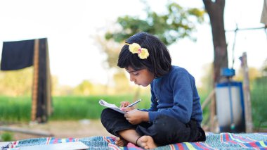 Küçük Hintli kız deftere yaz sezonunun arka planını yazıyor..