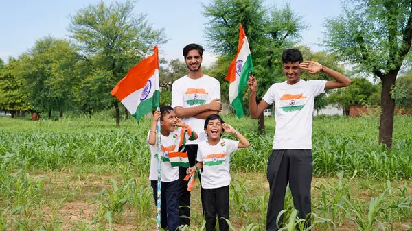 Stock image kids with family members wearing Indian flag logo design t shirt and holding, waving or running with Tricolour with greenery in the background, celebrating Independence or Republic day