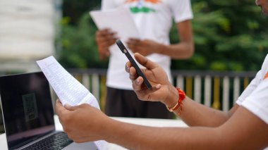 Genç Hintli adam cep telefonu ve laptop kullanarak faturaları ödüyor. QR kod taraması ve ödeme konsepti. Evden çalış.