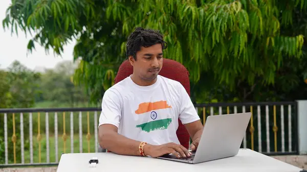 stock image Young Indian man doing work from home using laptop. Young boy sitting on terrace and doing office work.