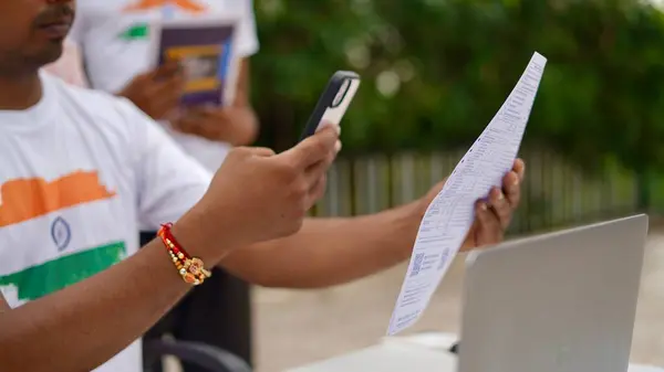 stock image Young Indian man paying bills using mobile and laptop. QR code scan and pay concept. Work from home