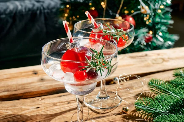 Christmas refreshment drink mimosa, punch or cranberry margarita cocktail serving in christmas ornaments and martini drinking glasses. Delicious icy drink idea for christmas and winter holiday party.