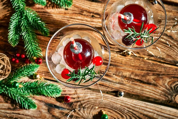 Christmas refreshment drink mimosa, punch or cranberry margarita cocktail serving in christmas ornaments and martini drinking glasses. Delicious icy drink idea for christmas and winter holiday party.