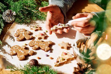 Karanfilli Noel kurabiyesi süsleyen kadın elleri zencefilli kurabiye, zencefilli ekmek adam, Noel ağacı ve yıldızlı, renkli şekerli bademlerle süslenmiş. Noel ve yeni yıl gelenekleri..