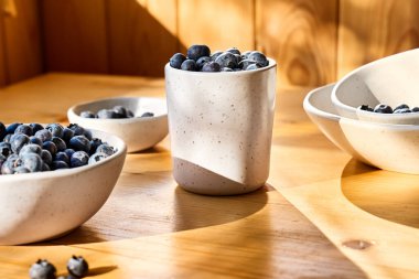 Fresh organic blueberries. Juicy ripe bilberry in white bowl on wooden table. Antioxidant and healthy eating concept.