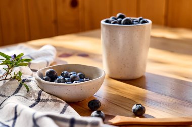 Fresh organic blueberries. Juicy ripe bilberry in white bowl on wooden table. Antioxidant and healthy eating concept.